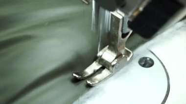 Dikiş makinesinin yakın görüntüsü. Terzi, tekstil fabrikasında profesyonel bir makineyle dikiş dikiyor.