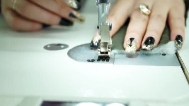 Dikiş makinesinin yakın görüntüsü. Terzi, tekstil fabrikasında profesyonel bir makineyle dikiş dikiyor.