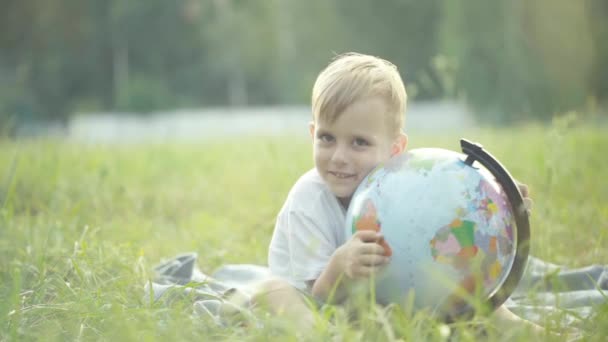 Ein Kleiner Junge Umarmt Eine Weltkugel Und Lächelt Zeitlupe Sonnenuntergang — Stockvideo