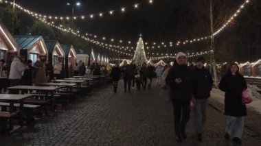 Bukovel tatil köyü, Ukrayna: 08 Aralık, 2024. Şehrin sokaklarında yılbaşı ışıkları. İnsanlar akşamları yürüyor.