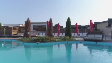 Yeşillik ve binalarla çevrili yüzme havuzu.