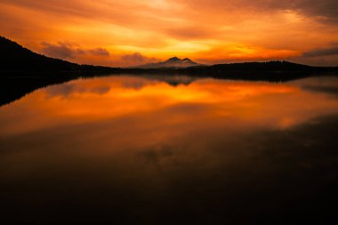 Kuzey Bohemya 'daki gölün yansımalarıyla destansı bir gün batımı. Güneşin tüm gökyüzünü renklendirdiği nefes kesici an.