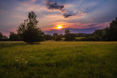 Güney Bohemya 'nın kırlarında romantik, renkli bir gün batımı. Güneşin tüm gökyüzünü ve bulutları renklendirdiği nefes kesici bir an..