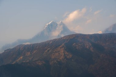 Machapuchare 'nin karla kaplı zirvesinin nefes kesen manzarası bulutlar Nepal' deki büyük Himalayalar 'daki dağları usulca sardığında.