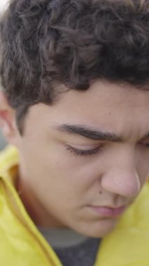 İspanyol üzgün gencin dikey yakın plan portresi aşağı bakıyor, sonra kameraya bakıyor..