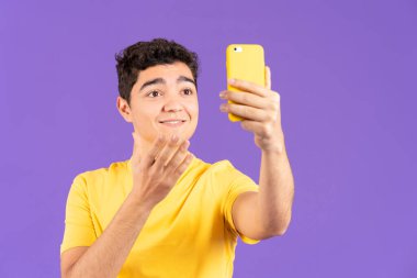 Hispanic influencer boy live streaming and talking on phone isolated on purple background