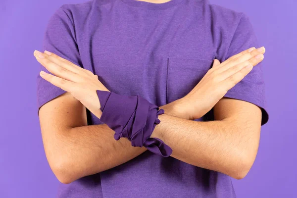 Crossed arms of feminist man saying no isolated on purple background. Gender violence concept