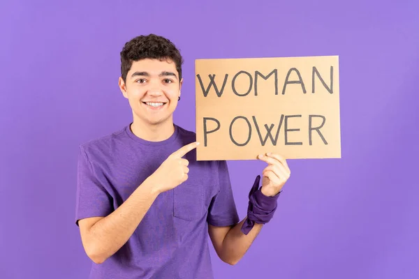 Hispanic teenager boy pointing at billboard isolated on purple background. Feminism and woman power concept.
