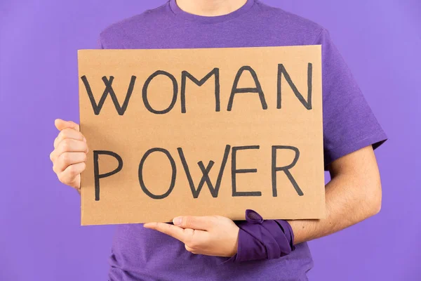 Closeup of feminist activist holding billboard with woman power message isolated on purple background