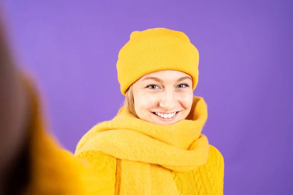 紫の背景に隔離された黄色の冬服を着て美しい女性のセルフィーの肖像画 — ストック写真