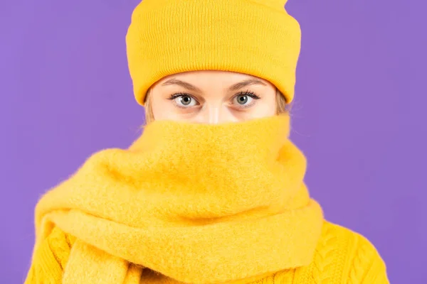 紫色の背景に隔離されたスカーフで顔を覆う青い目の冬服の女性の肖像 — ストック写真