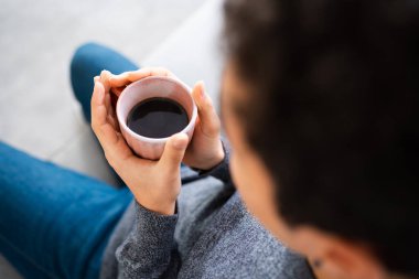Elinde bir fincan kahve tutan tanınmayan bir adamın arka görüntüsü.