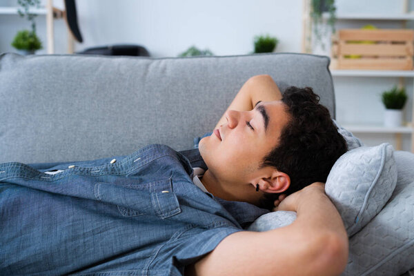 Латиноамериканец-подросток расслабляется на диване с руками за головой