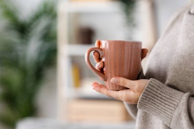 Closeup of female hands holding cup of hot drink like coffee or tea