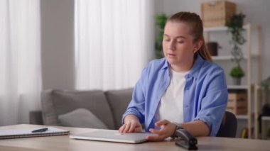 Freelancer working at home on laptop , closing it and sending voicemail on smartwatch. Then leaving the place.