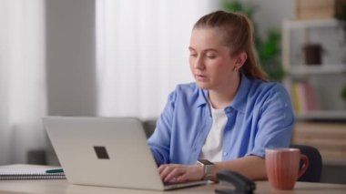 Pretty woman working from home on laptop and drinking cup of coffee