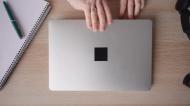 View from above of hands opening laptop and starting to type on keyboard. 