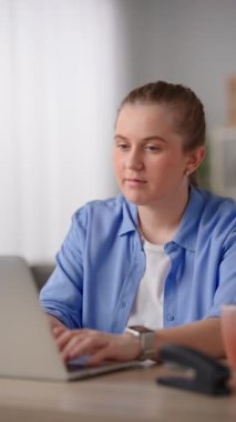 Young freelancer woman working on laptop and drinking a cup of coffee.