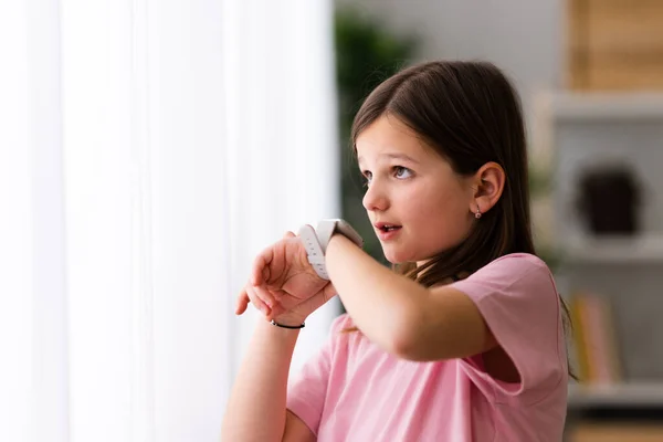 Little girl talking on smartwatch at home