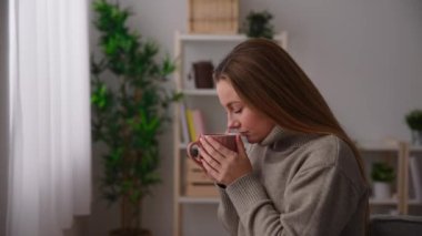 Young contemplative woman thinking on future while drinking cup of coffee or tea