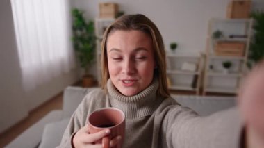 Camera point of view of young pretty woman live streaming on phone in an apartment