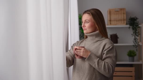 女人从窗户往外看 喝咖啡或茶 — 图库视频影像