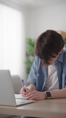 Cute teenager boy learning from home watching online tutorial. Student at virtual classroom