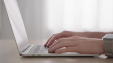 Closeup of hands typing on laptop keyboard with selective focus