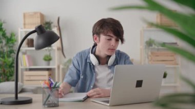 Teenager boy e-learning at home. Student learning from home using the laptop to have a live streaming class.