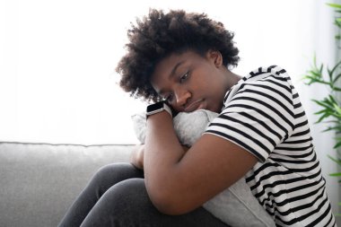 Üzgün Afrikalı Amerikalı genç bir kadın yastığı kucaklıyor. Depresyon ve akıl sağlığı kavramı.