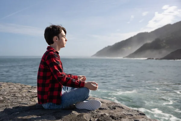 Genç Bir Çocuk Sahilde Meditasyon Yapıyor Duvarda Oturuyor — Stok fotoğraf