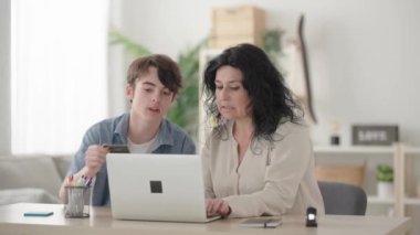 Anne ve oğlu online alışveriş yapıyor ve birlikte alışverişi kutluyorlar.