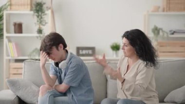 Anne, onu görmezden gelen ergen oğluyla konuşmaya çalışıyor. Hüsrana uğramış kadın, azarlayan genç çocuk.