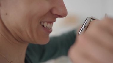 Uyanık telefondan mesaj gönderen kadına yakın çekim. Ağız konuşuyor. .
