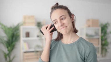 Latin kökenli genç bir kadın sesli mesajları dinliyor ve sonra da cevap vermek için telefonla konuşuyor..