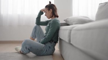 İspanyol genç kadın evde yerde otururken depresyona giriyor.