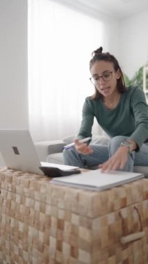 Kızgın kadın dizüstü bilgisayardaki bir görüntülü aramada bağırıyor. Evinde çalışan İspanyol bir genç.