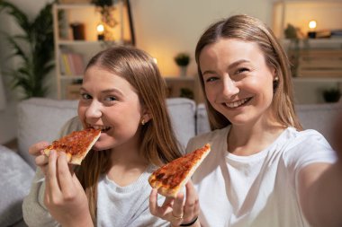 Geceleri pizza yerken selfie çeken iki arkadaş ya da kız kardeş. Genç kadınlar yemek yerken canlı yayında.