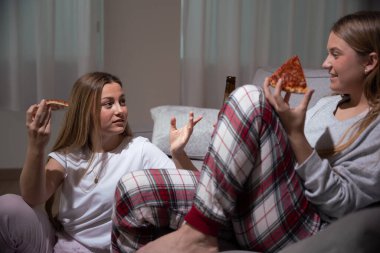 Arkadaşlar kanepede yemek yiyor. Pijama giyen, pizza yiyen ve geceleri konuşan rahibeler..