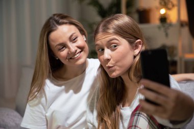 Geceleri evde selfie çeken iki genç kadın..