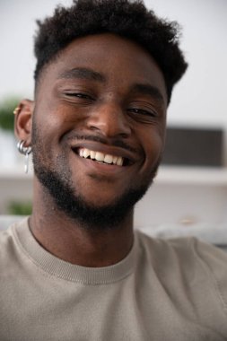 Kameraya bakıp gülümseyen genç siyahi adamın portresi..