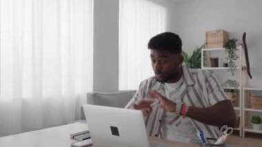 Öfkeli Afrikalı Amerikalı genç adam dizüstü bilgisayardaki video görüşmesini bitirdikten sonra ayağa kalktı.