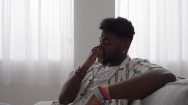 Siyah genç adam kanepede oturuyor ve kamerayla konuşuyor. Afrikalı Amerikalı canlı yayın