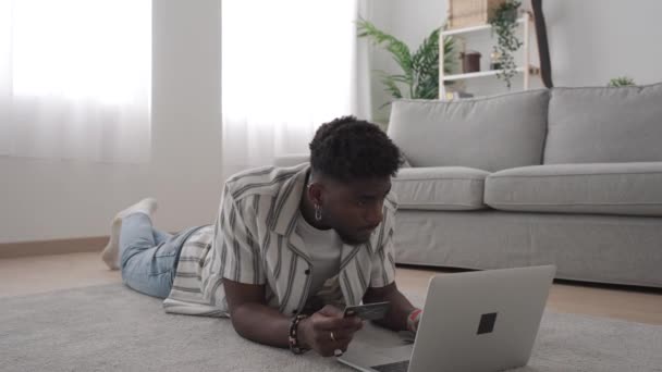 Zwarte Jongeman Koopt Online Laptop Terwijl Hij Vloer Ligt Afro — Stockvideo