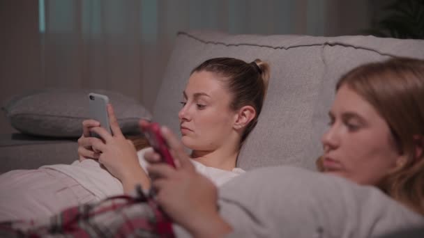 Скучные Молодые Женщины Лежащие Ночью Диване Сестры Игнорируют Друг Друга — стоковое видео