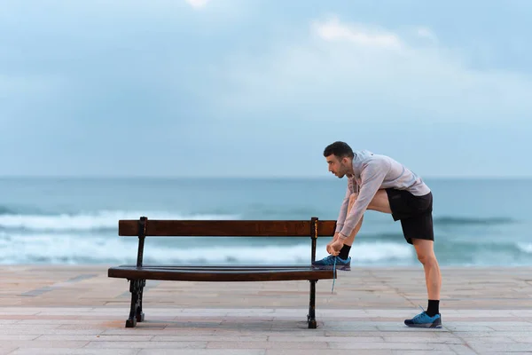 Dışarıdaki Bankta Ayakkabı Bağcıkları Bağlayan Bir Koşucu Sahil Şeridinde Motivasyonlu — Stok fotoğraf