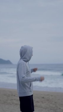 Kumsala gelen ve deniz manzaralı bir koşucu. Sporcu başlığı çıkarıyor