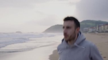 Sahilde koşan sporcunun ön taraftaki yakın çekim görüntüsü. Açık havada antrenman yaparken çekilen fotoğraf.