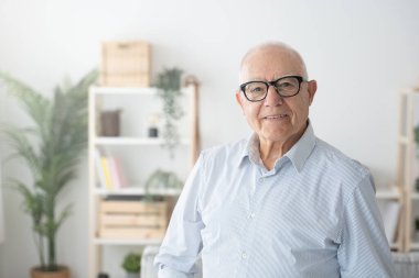 Evde kameraya bakan gülümseyen yaşlı bir adamın portresi..