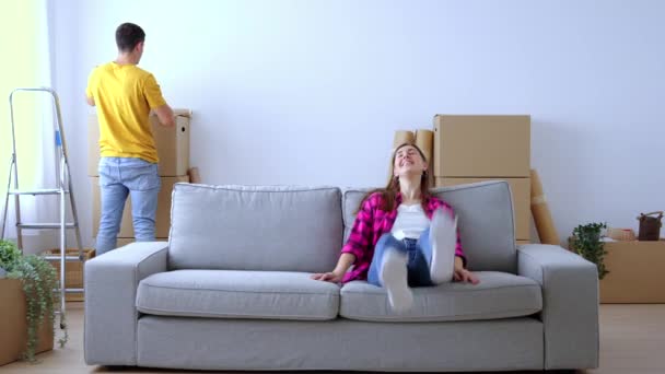 若いカップルは新しい家のソファに座ってリラックスしています 家のコンセプトを移動 — ストック動画